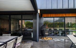 Pergola sombre abritant un salon extérieur près d'une maison